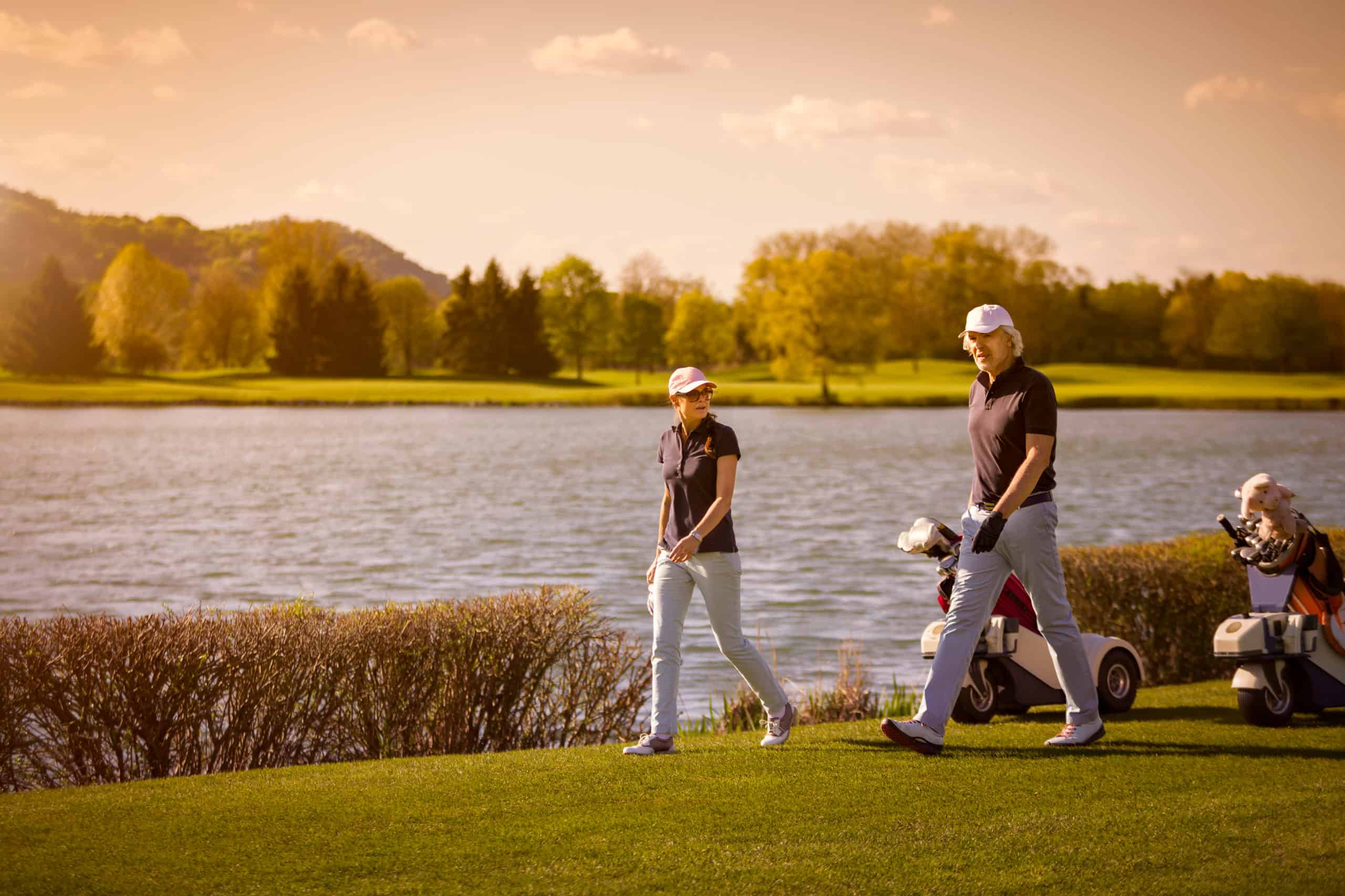 Senior couple walking on golf course. Golf Journey 365